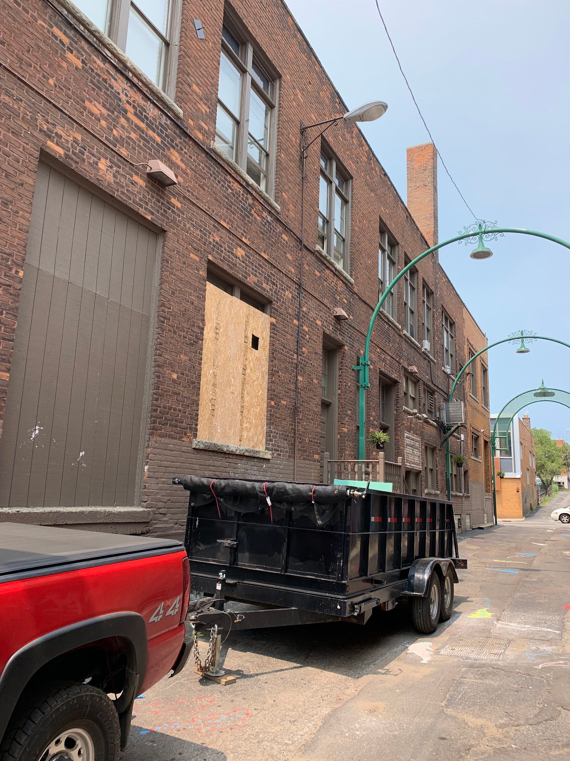 A dumpster is parked in front of a brick building.