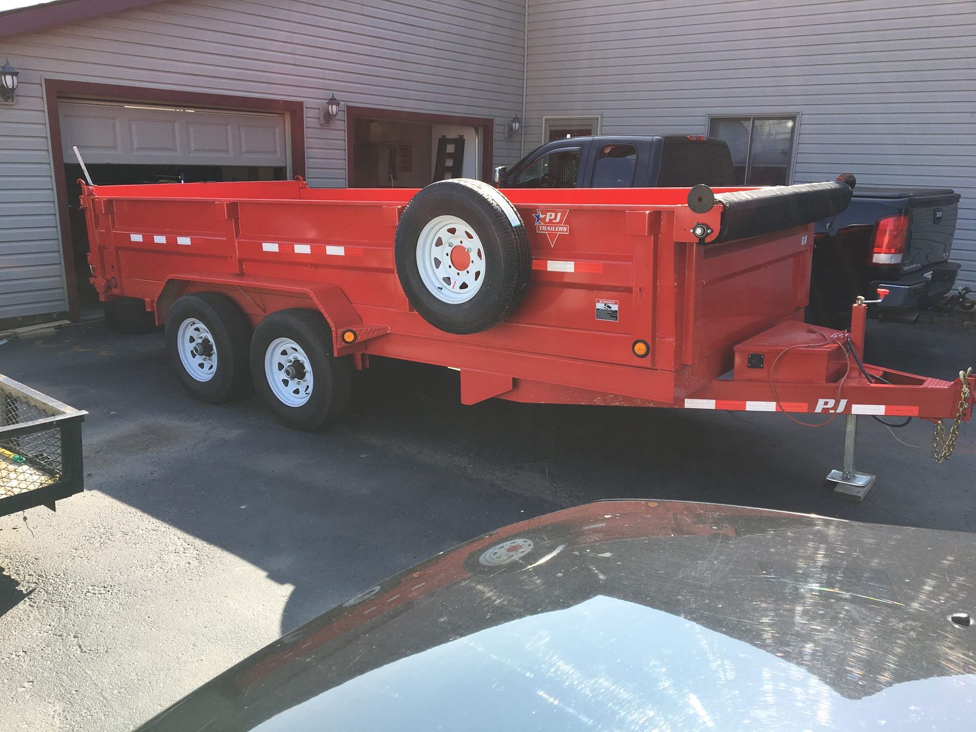 A red dump trailer is parked in front of a house