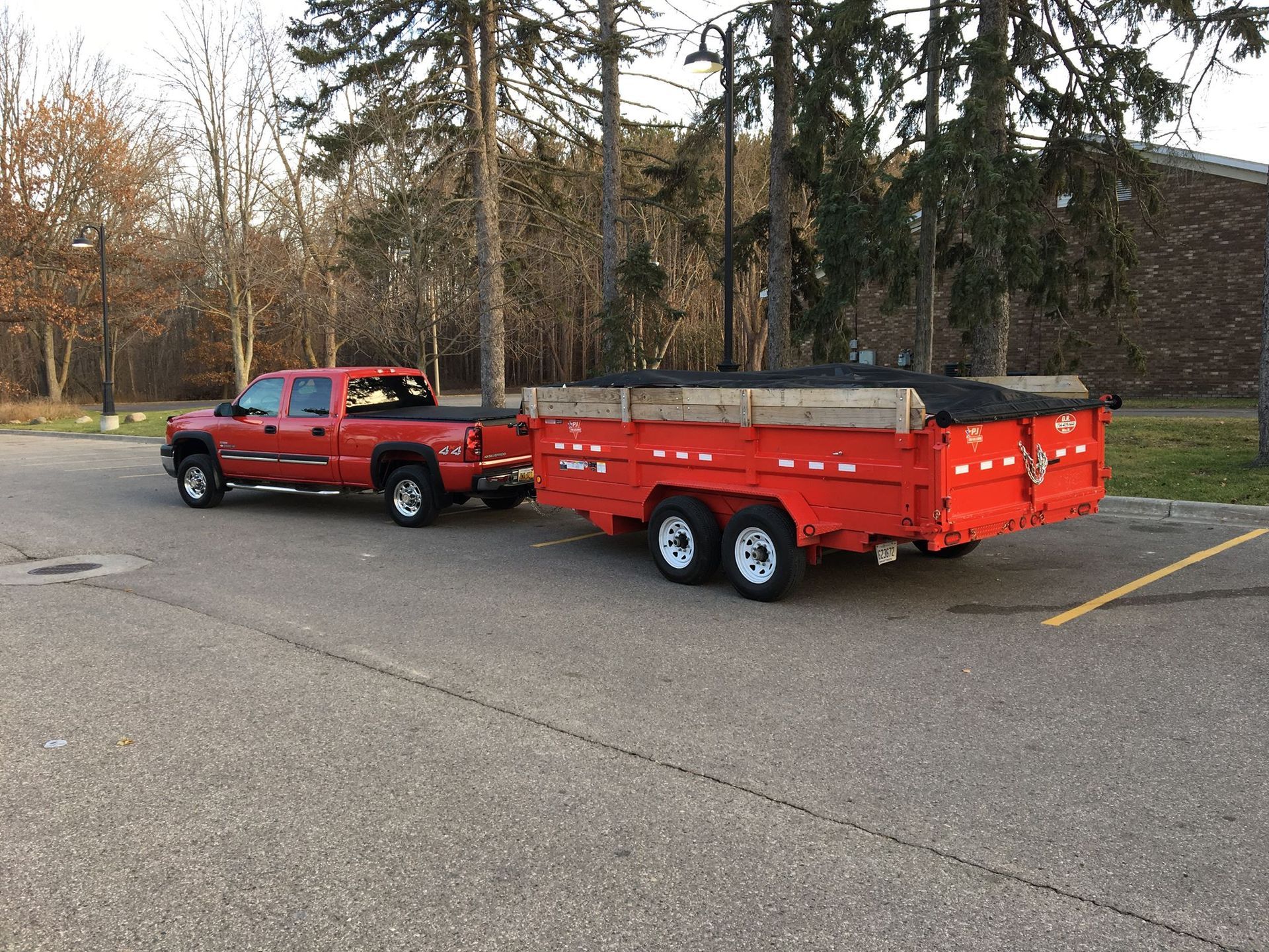 A red truck is pulling a red trailer in a parking lot.