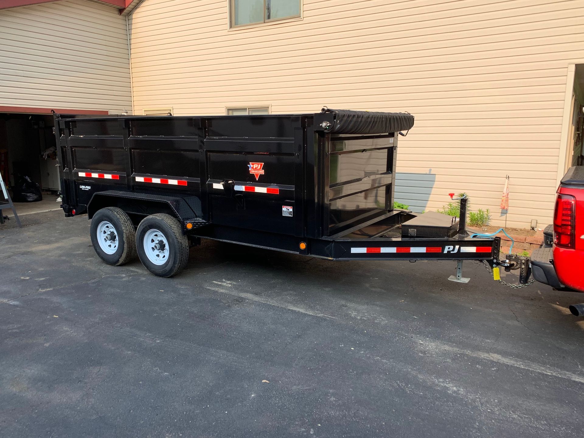 A dump trailer is parked in a parking lot next to a truck.