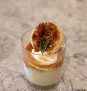 Vanilla ice cream sundae in a glass dish, topped with chopped pistachios on a marble counter