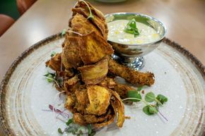 Crispy fried seafood tower on a white plate with a small cup of creamy sauce