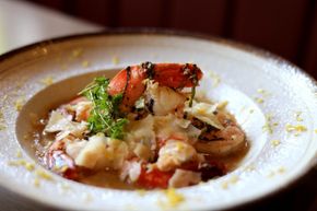 Close-up of a crab dish garnished with herbs on a white plate with sauce