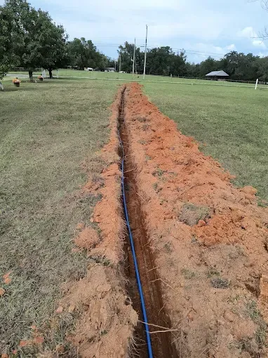 Brass irrigation backflow preventer with green-handled valves installed in the ground.