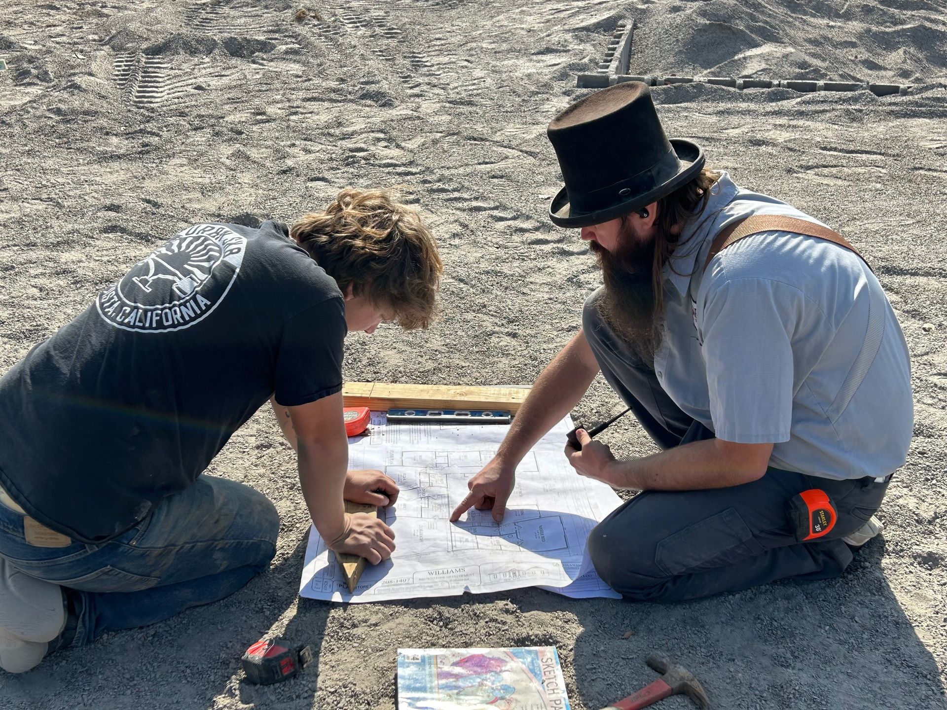 Plumber kneeling under a kitchen sink, working on the pipes. A toolbox sits on the floor.