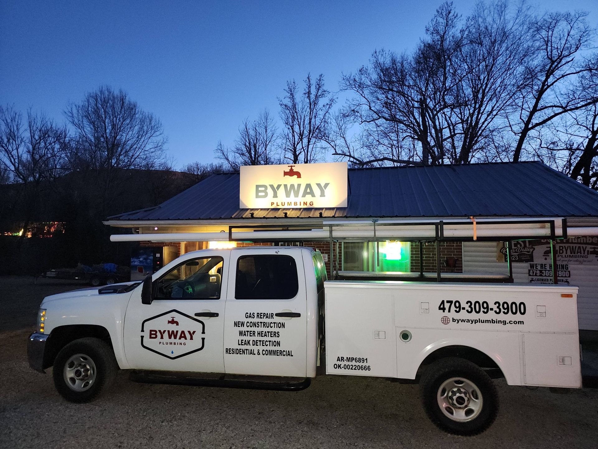 Man in burgundy shirt and baseball cap smiling, with glasses.