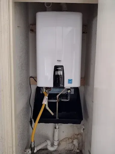 Laundry room with washer, storage shelves, water heater, and sink.