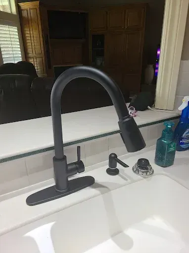Bathroom with white marble walls, glass shower, black and white tile floor, and a modern sink.