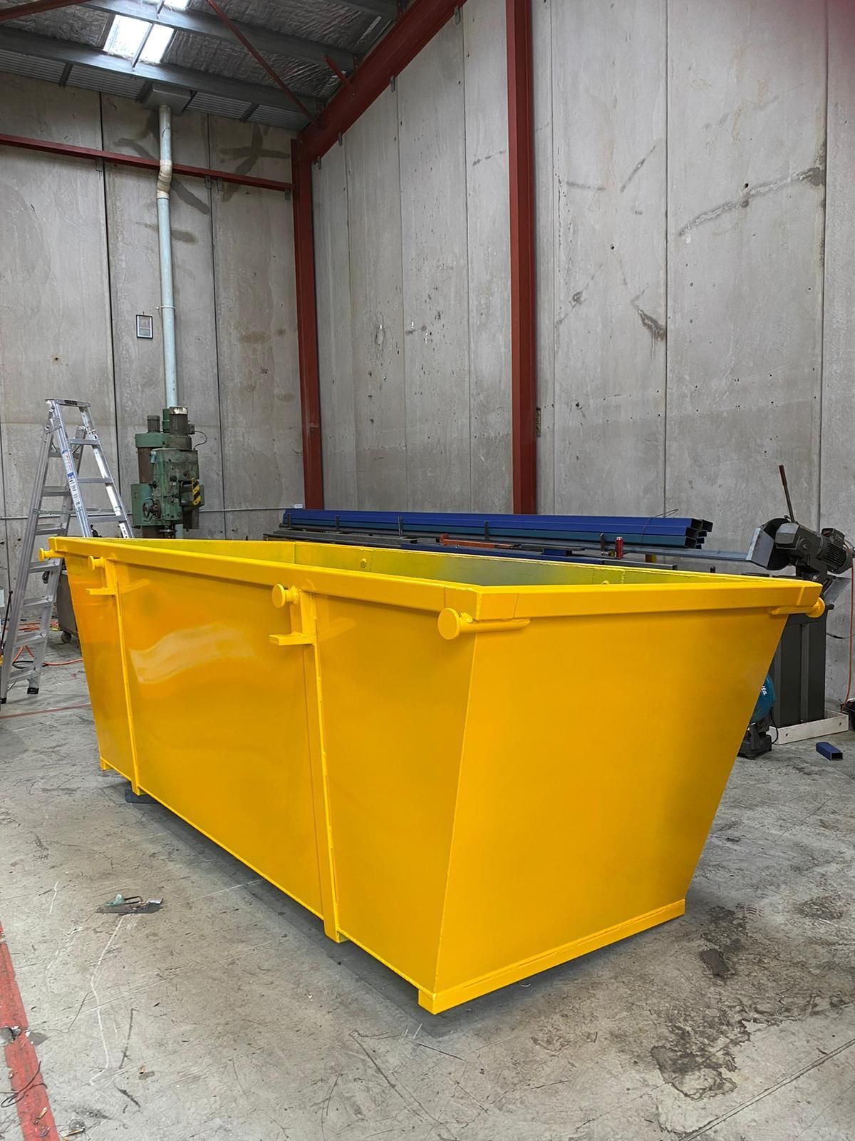 A stack of yellow dumpsters are sitting on the sidewalk in front of a building.