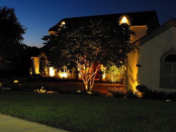 A house that is lit up at night with a tree in front of it
