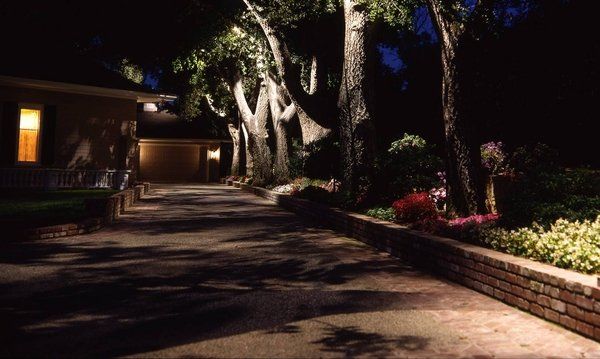 A driveway leading to a house is lit up at night.