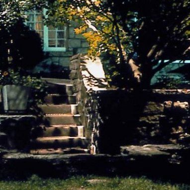 A stone wall with stairs leading up to a house
