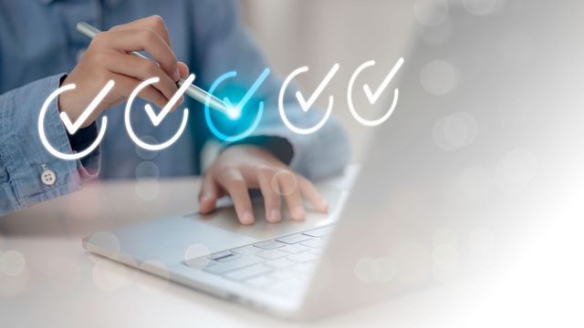 Person using a laptop, interacting with digital checkmarks.