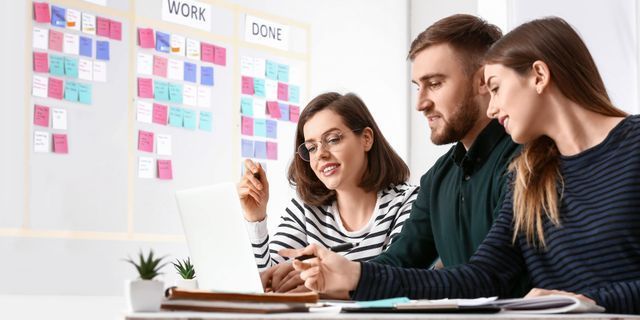 Man and woman looking at a laptop together, pointing at the screen in an office setting.