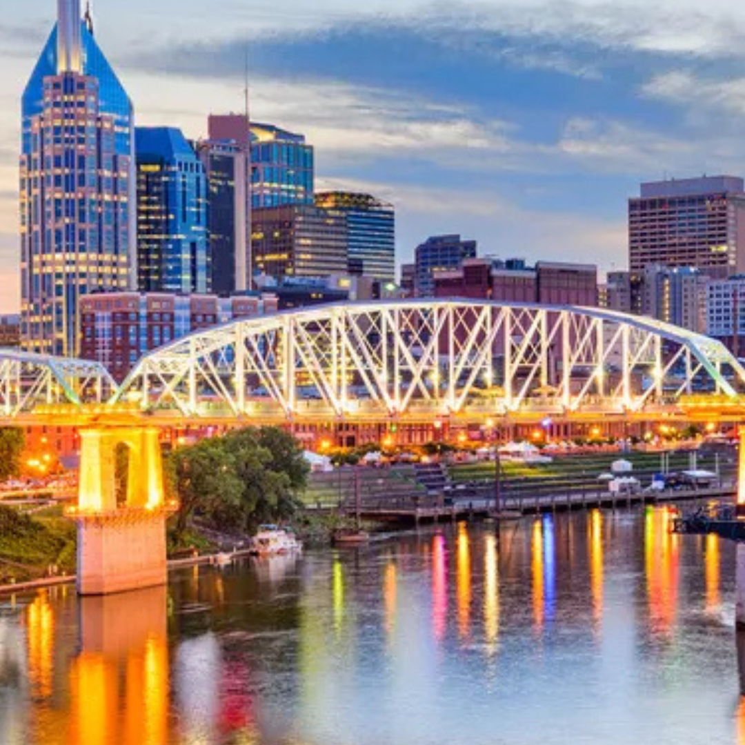 View of Nashville's skyline at dusk, with the illuminated John Seigenthaler Pedestrian Bridge spanning the Cumberland River.