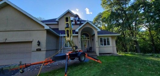 A man is working on the roof of a large house.
