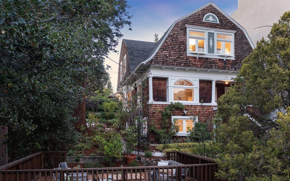 A large brick house with a balcony and trees in front of it.