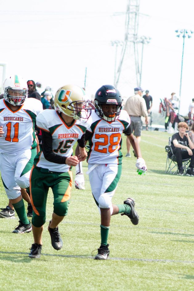 Football player in silver uniform runs with ball on a green field.