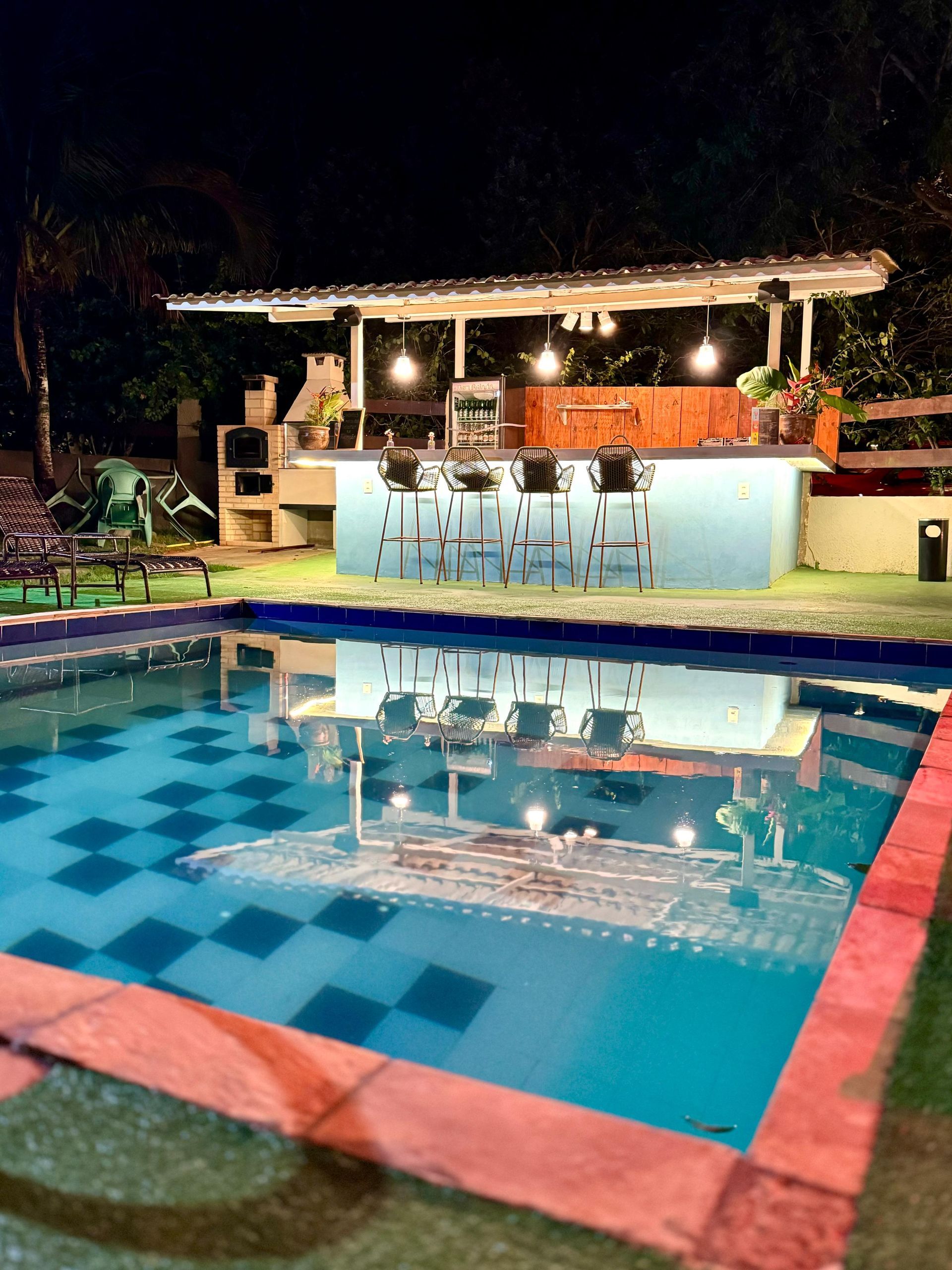 Uma grande piscina com um bar ao fundo à noite - Pousada-Estrelamar-Ferradura