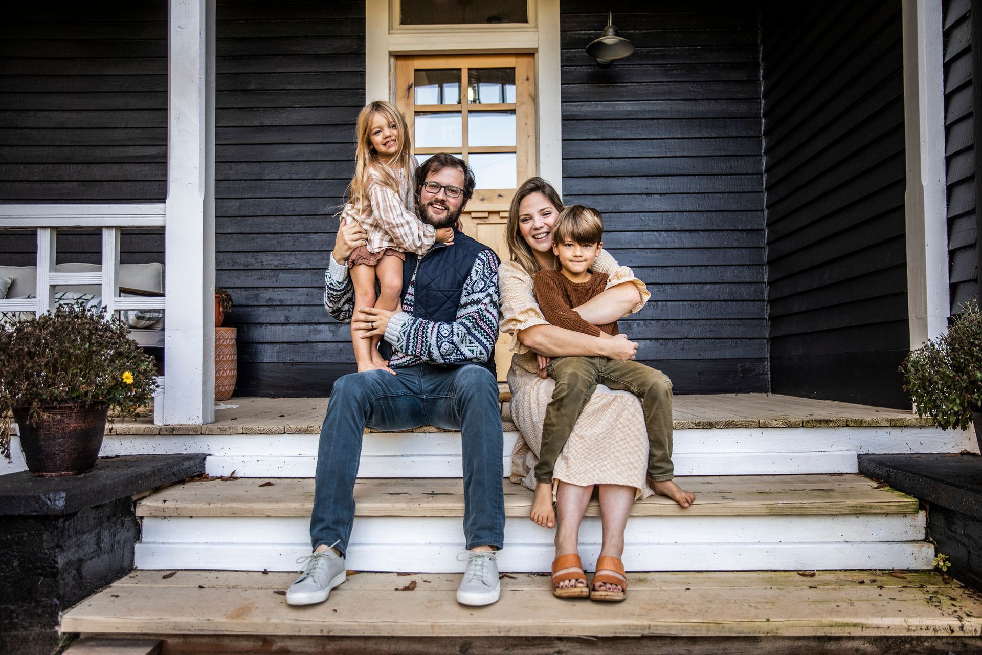 A family is sitting on the porch of their house.