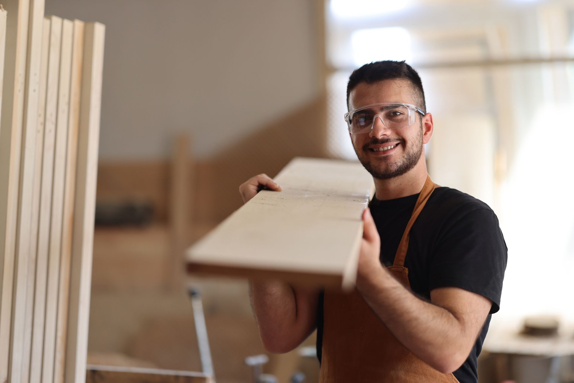 A man is holding a piece of wood in his hands in a workshop.