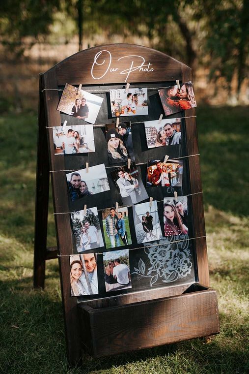 A wooden sign with pictures hanging on it is sitting on top of a lush green field.