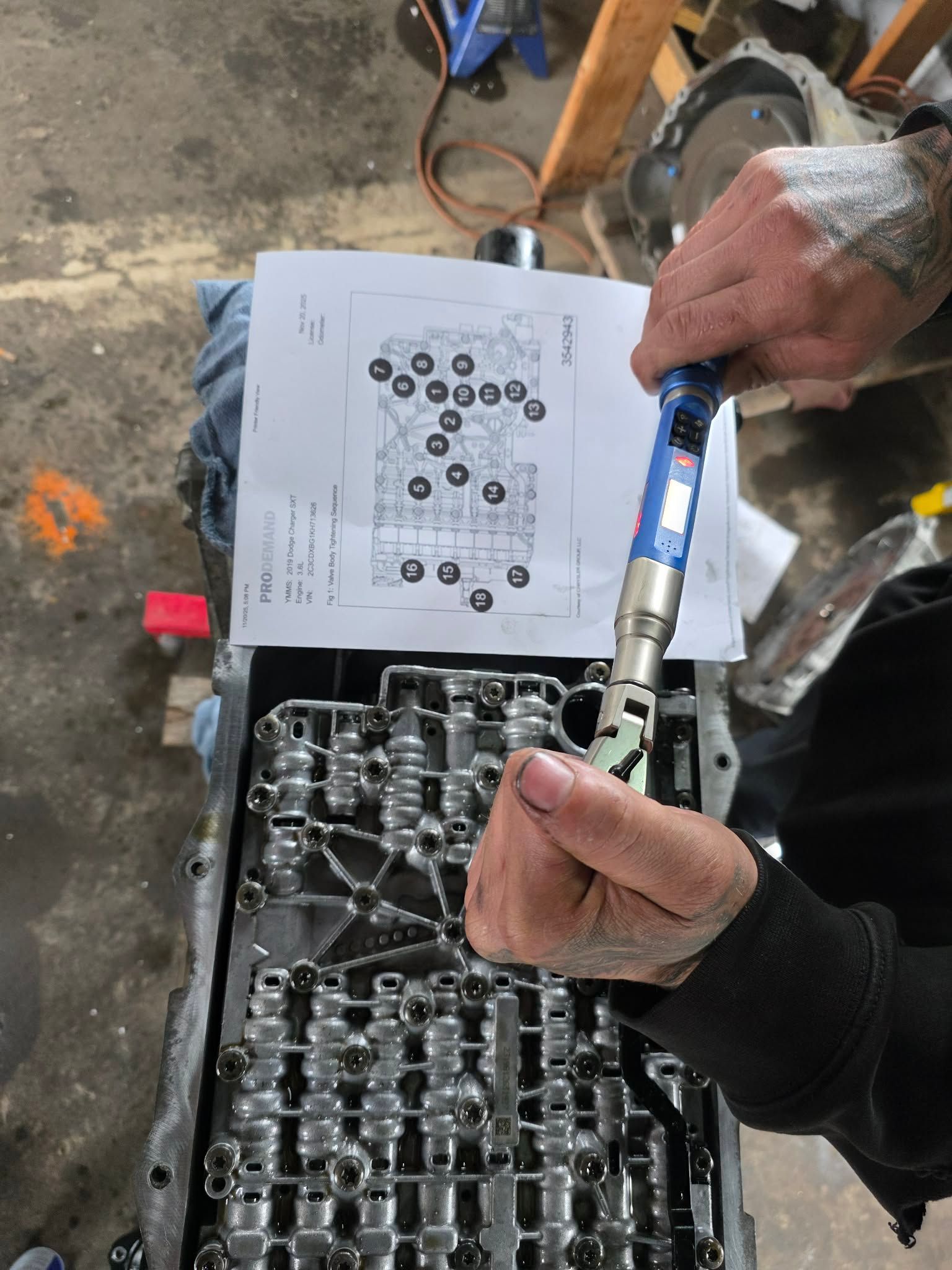 Person torques bolts on an automotive valve body, following a diagram. | Seth's Auto Care