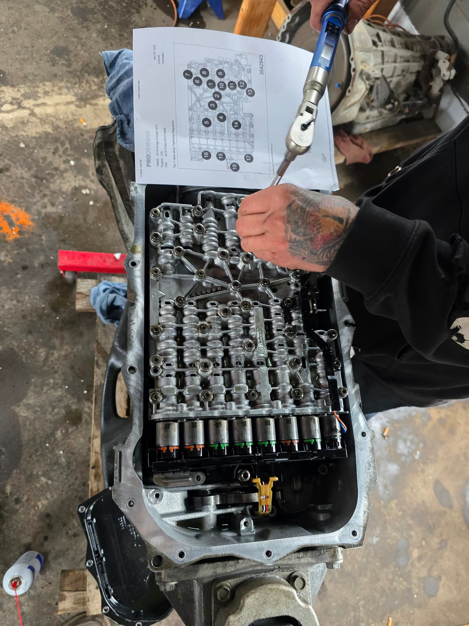 Person using a wrench on the opened transmission of a car, with a diagram. | Seth's Auto Care