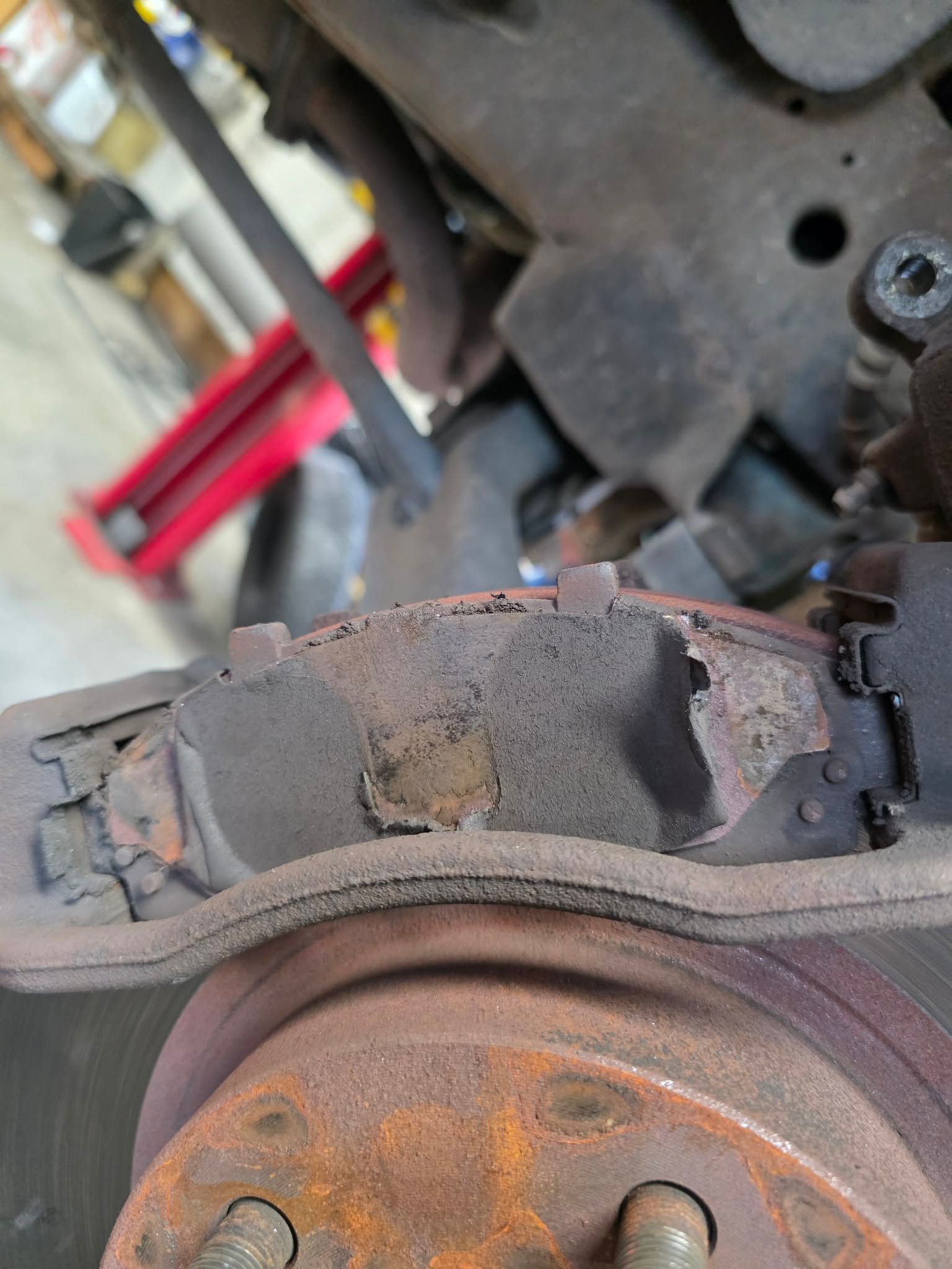Close-up of a worn brake pad against a rusty brake rotor; the pad is deteriorated. | Seth's Auto Care