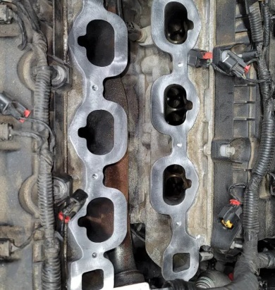 Close-up of a car engine's intake manifold ports, showing the exposed valve seats and surrounding components. | Seth's Auto Care