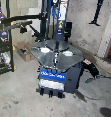 Tire changer machine in a garage setting with various tools. | Seth's Auto Care