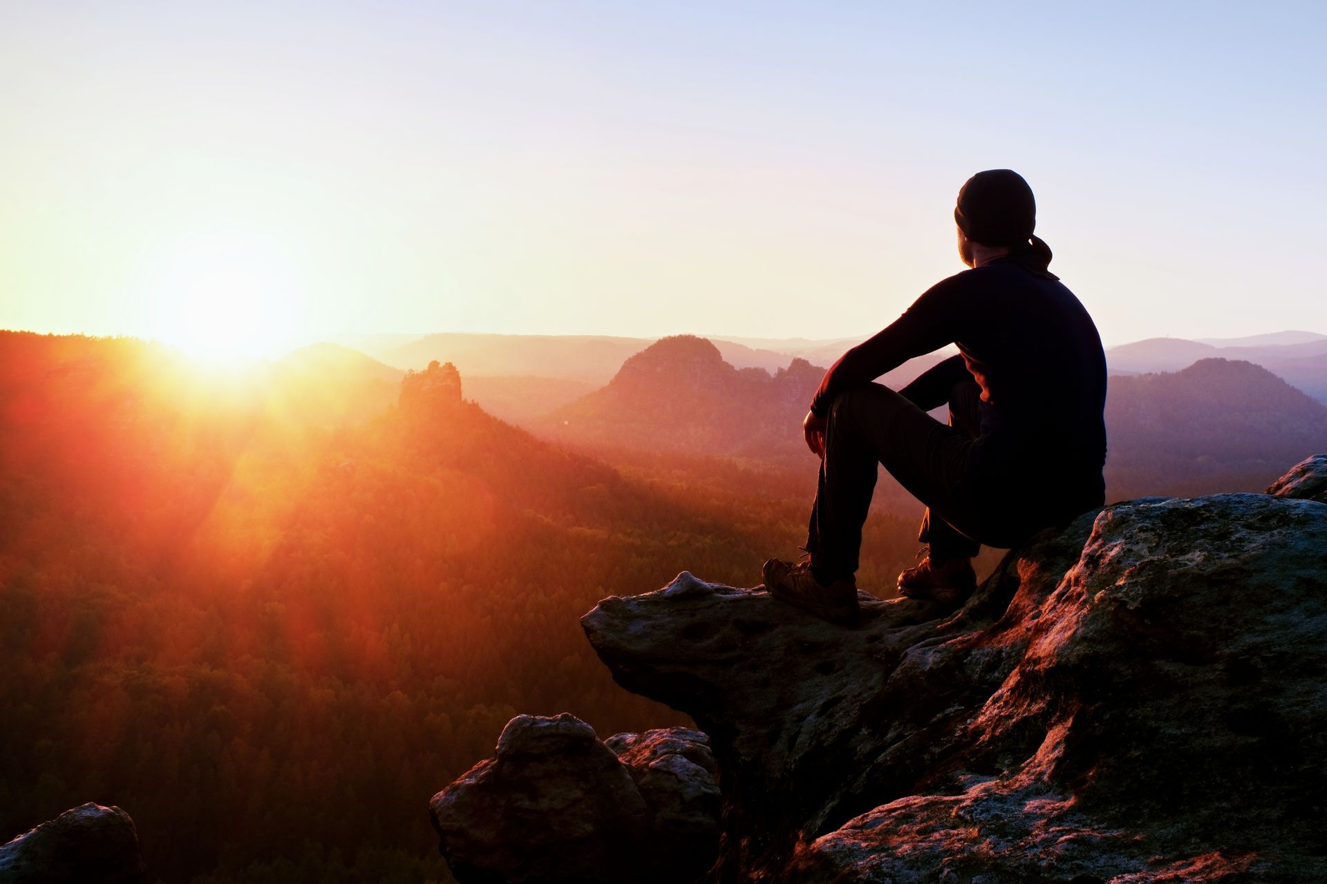Man Is Sitting on Top of a Mountain