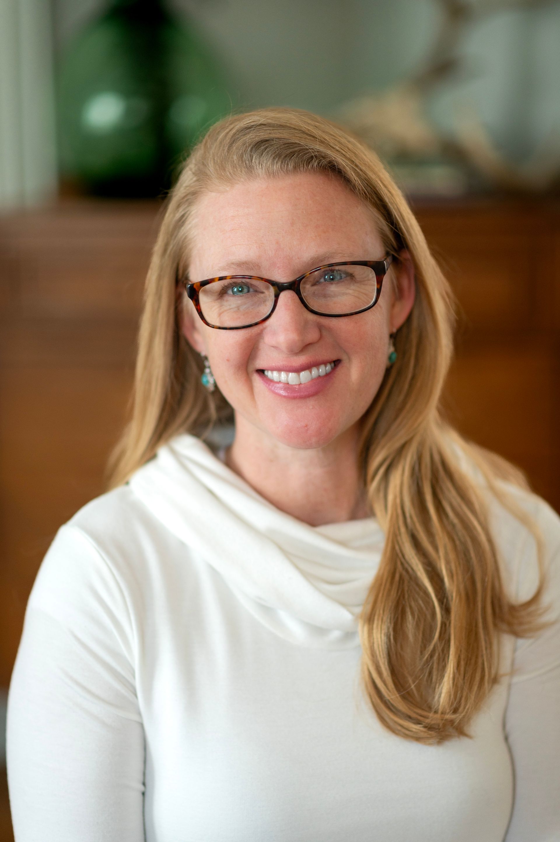 Person cleaning a brown table with a blue cloth and spray bottle, wearing pink gloves.