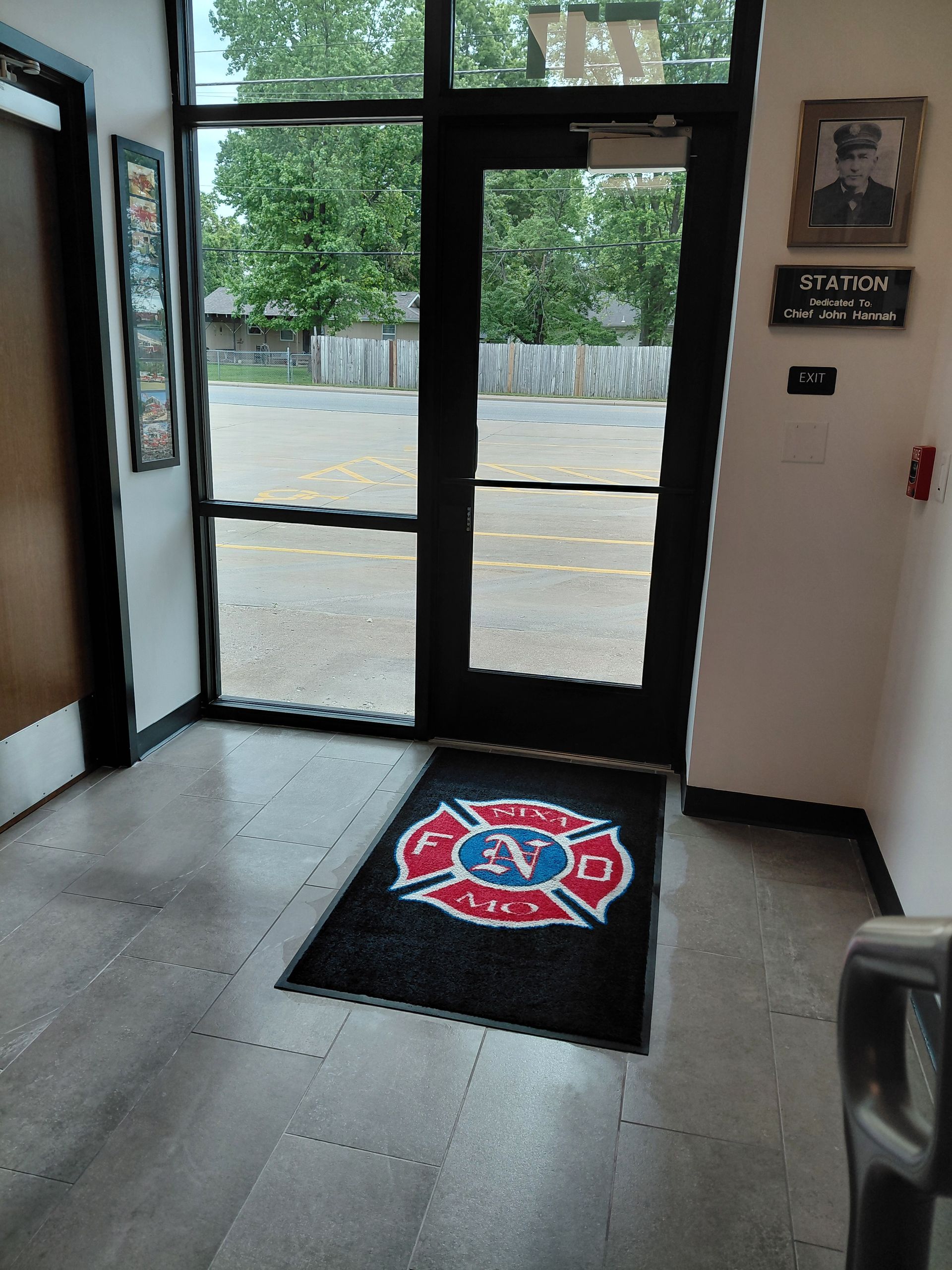 A person mops wet stairs, wearing an apron and gloves, with a cleaning cart and caution sign nearby.
