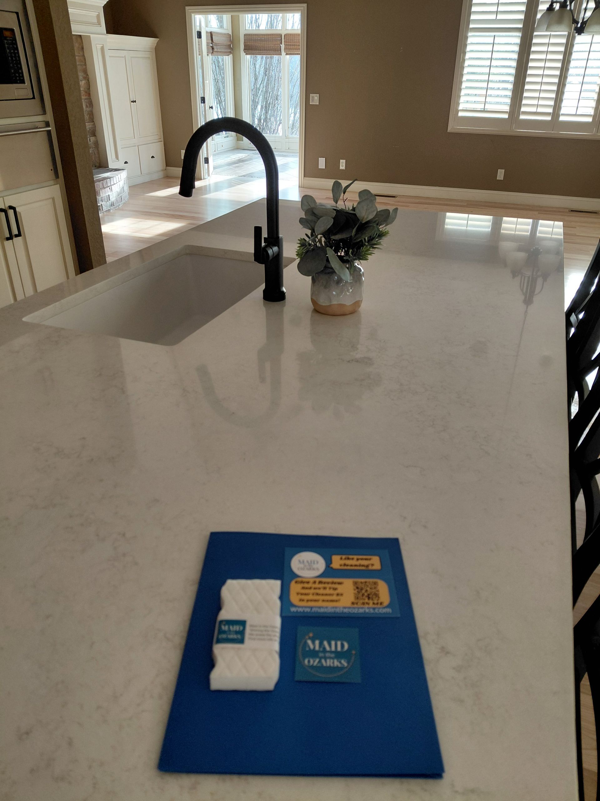 Person holding cleaning supplies, another mopping floor, in a well-lit room.
