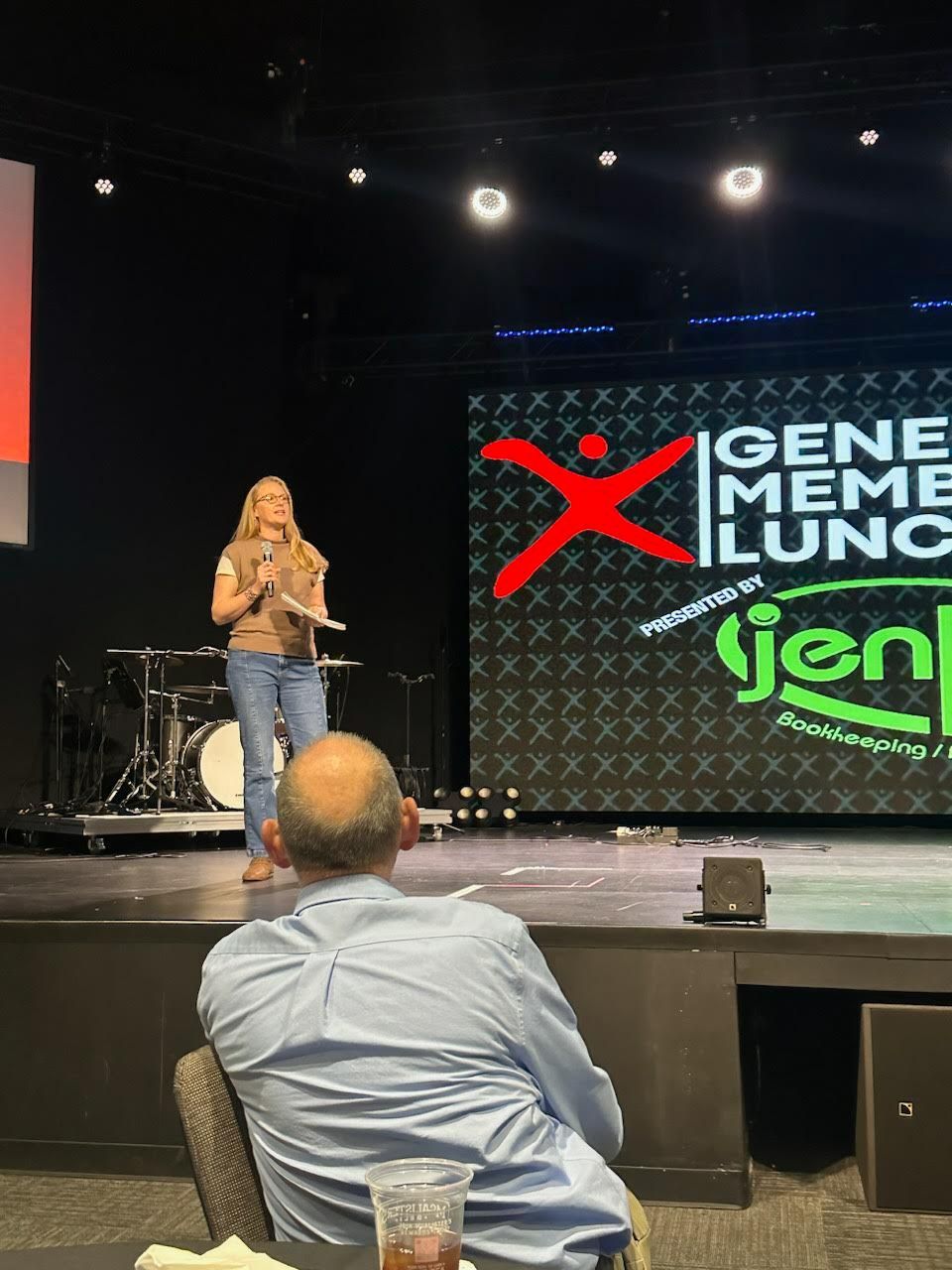 Woman speaking on stage at event, 