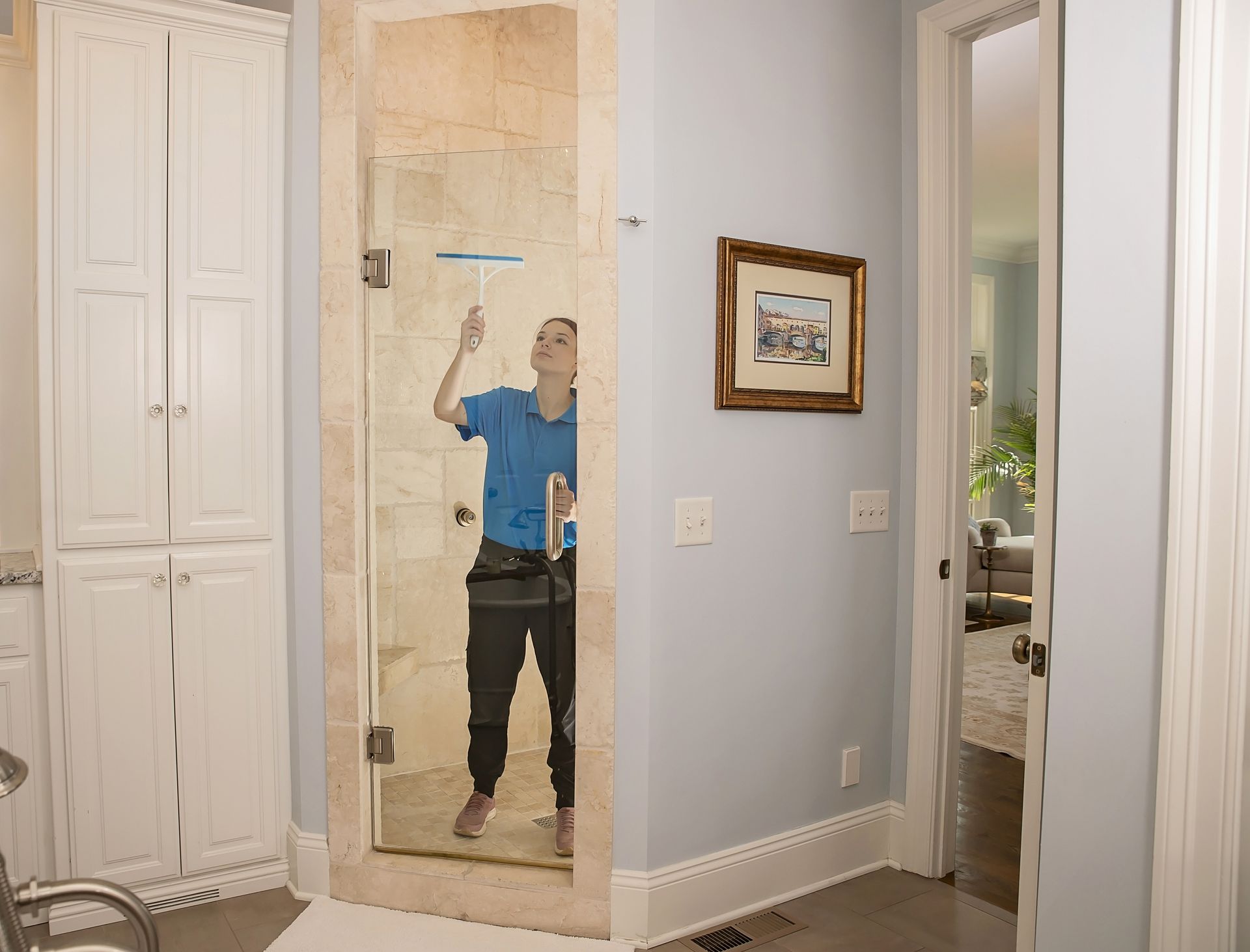 Person in yellow gloves cleaning a black stovetop with a pink cloth in a kitchen.