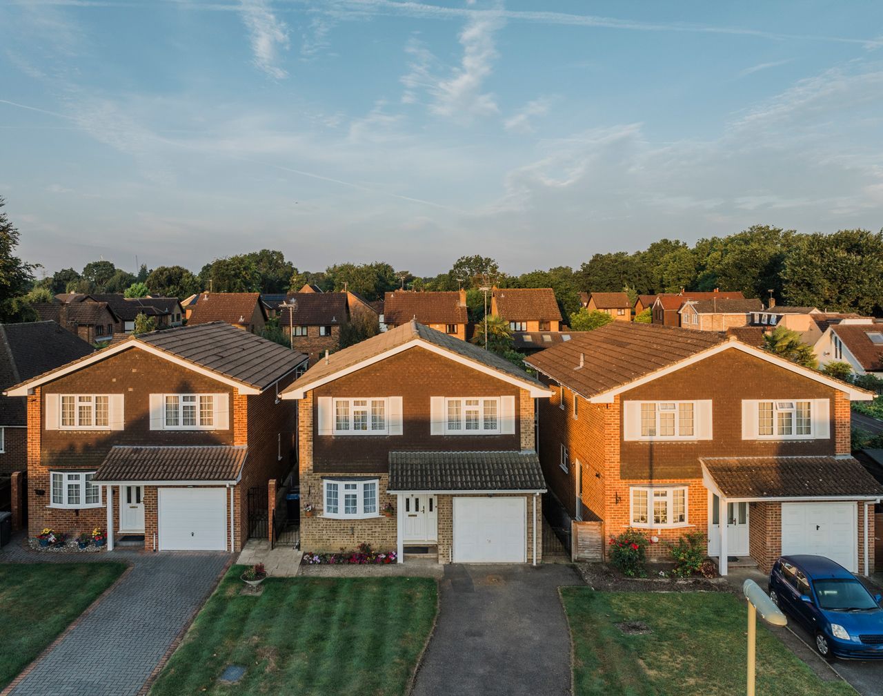 A row of houses with a blue car parked in front of them.