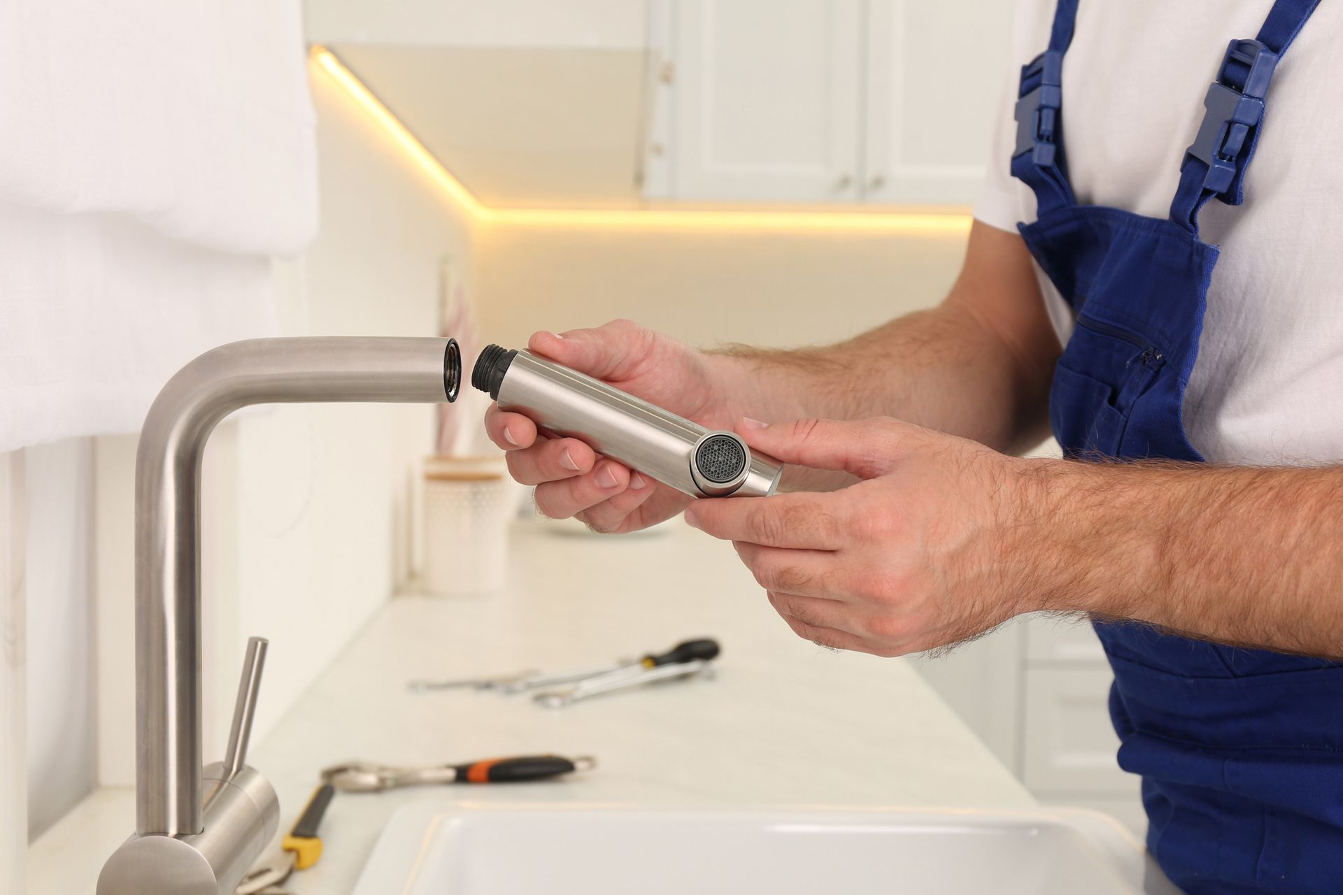 A man is fixing a faucet in a kitchen.