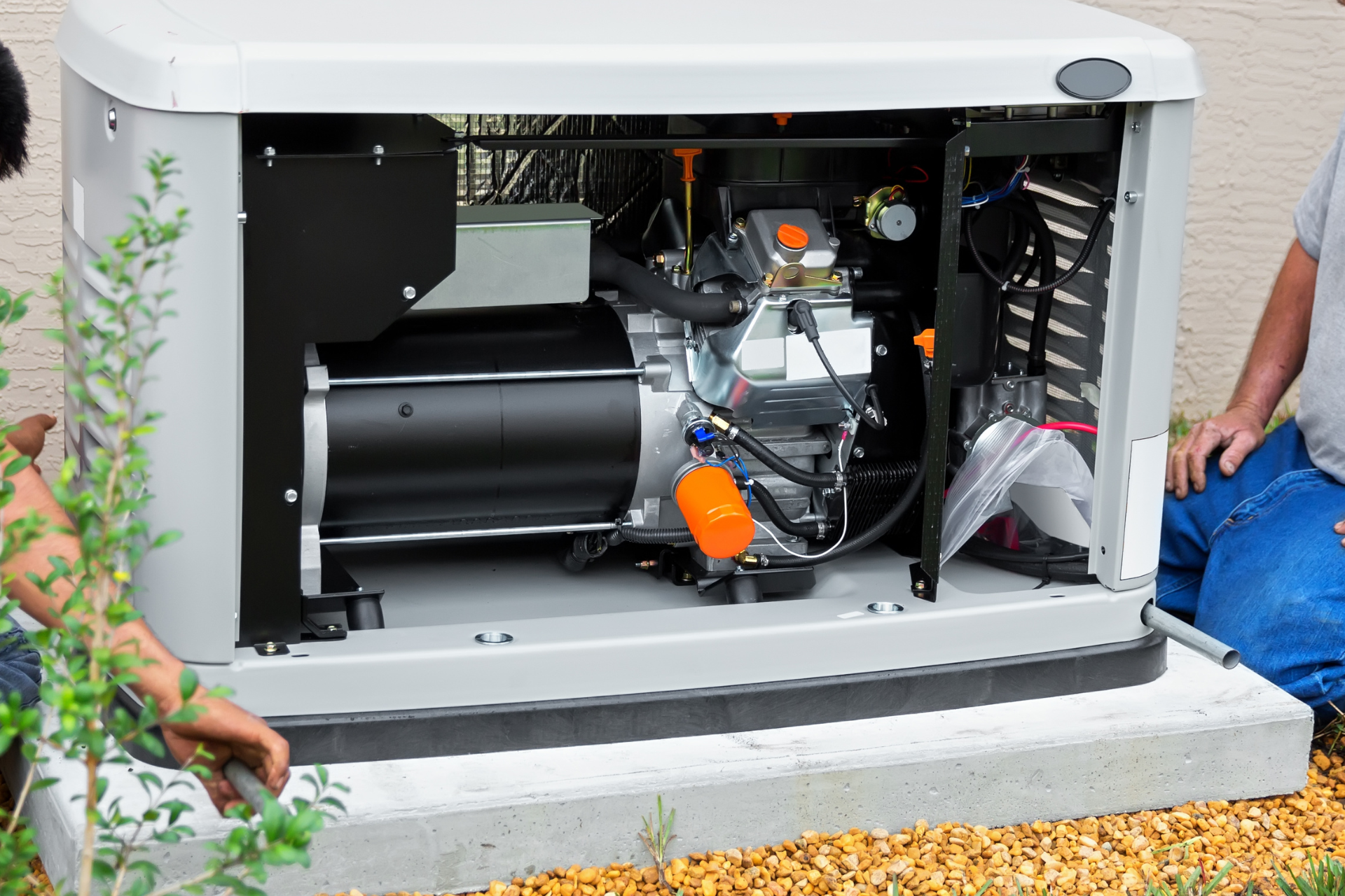 Generator with open side panel, on concrete base, showing internal engine components, with two people.