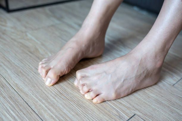A person 's bare feet are sitting on a wooden floor.
