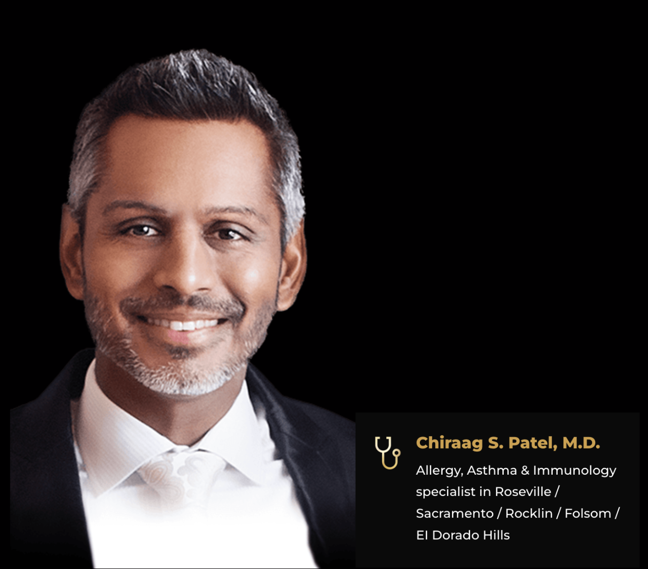 A smiling man with a beard is wearing a suit and tie