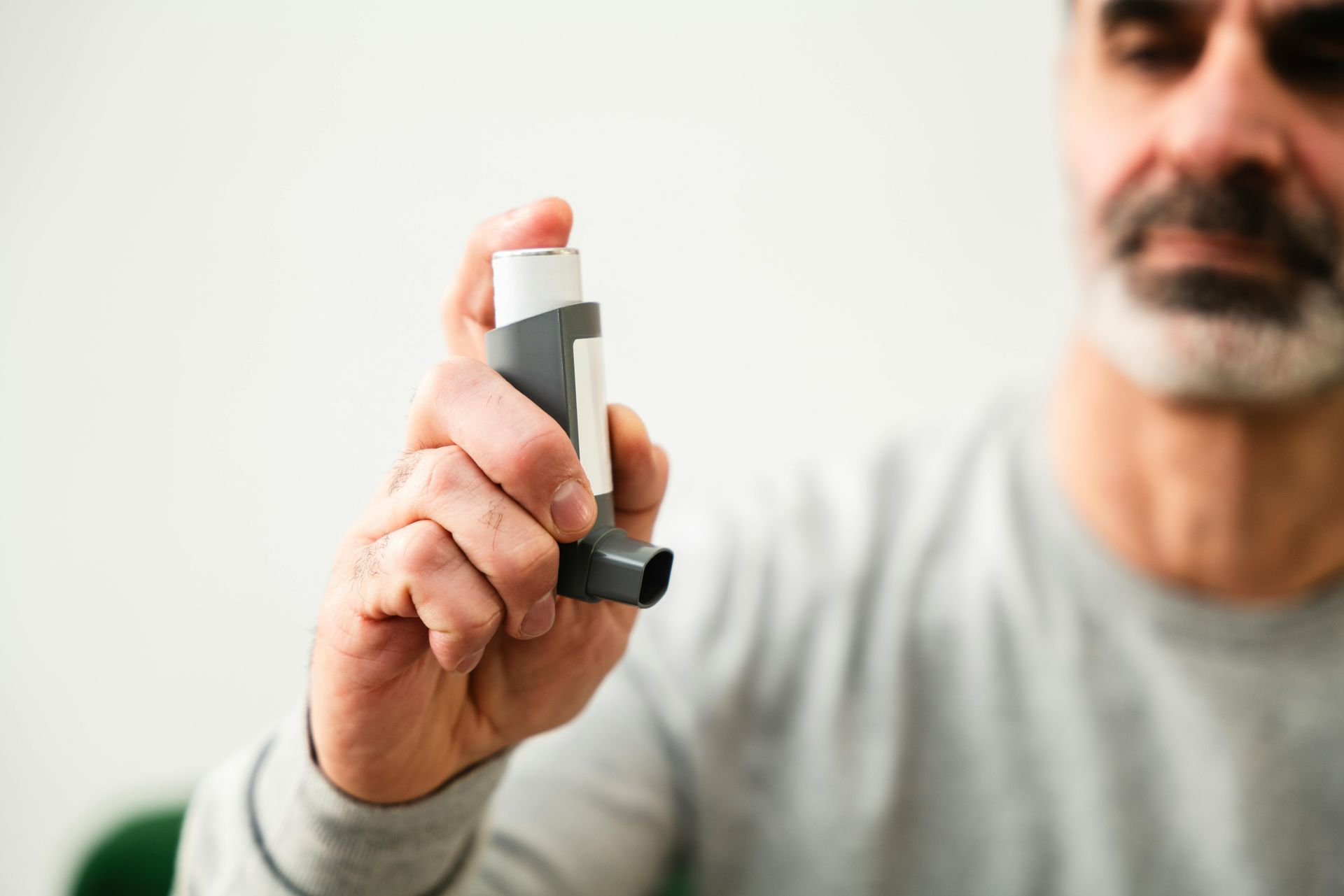 A man is holding an inhaler in his hand.