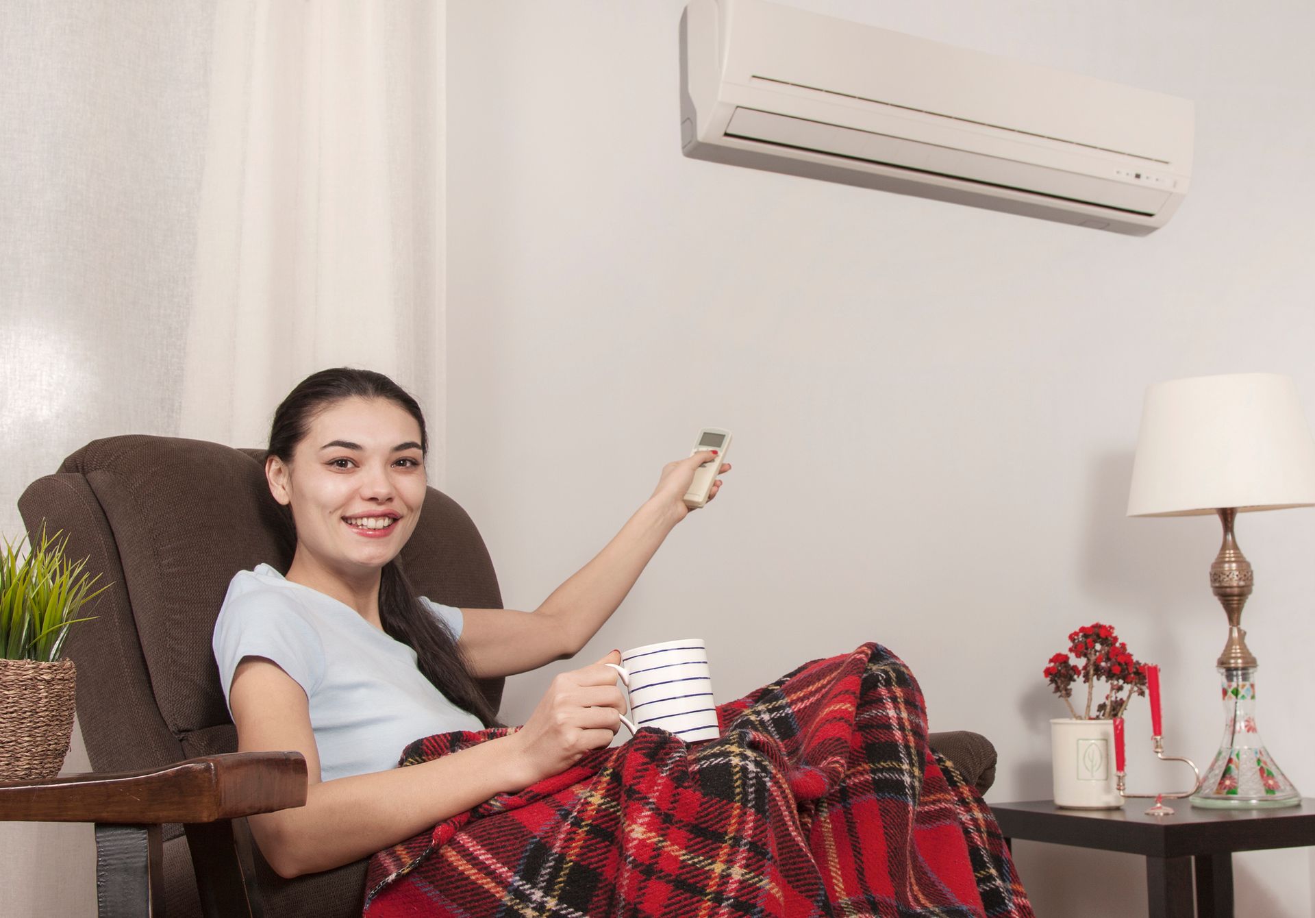 Woman using remote control of air conditioner in Concord, CA home, showcasing year-round heating and