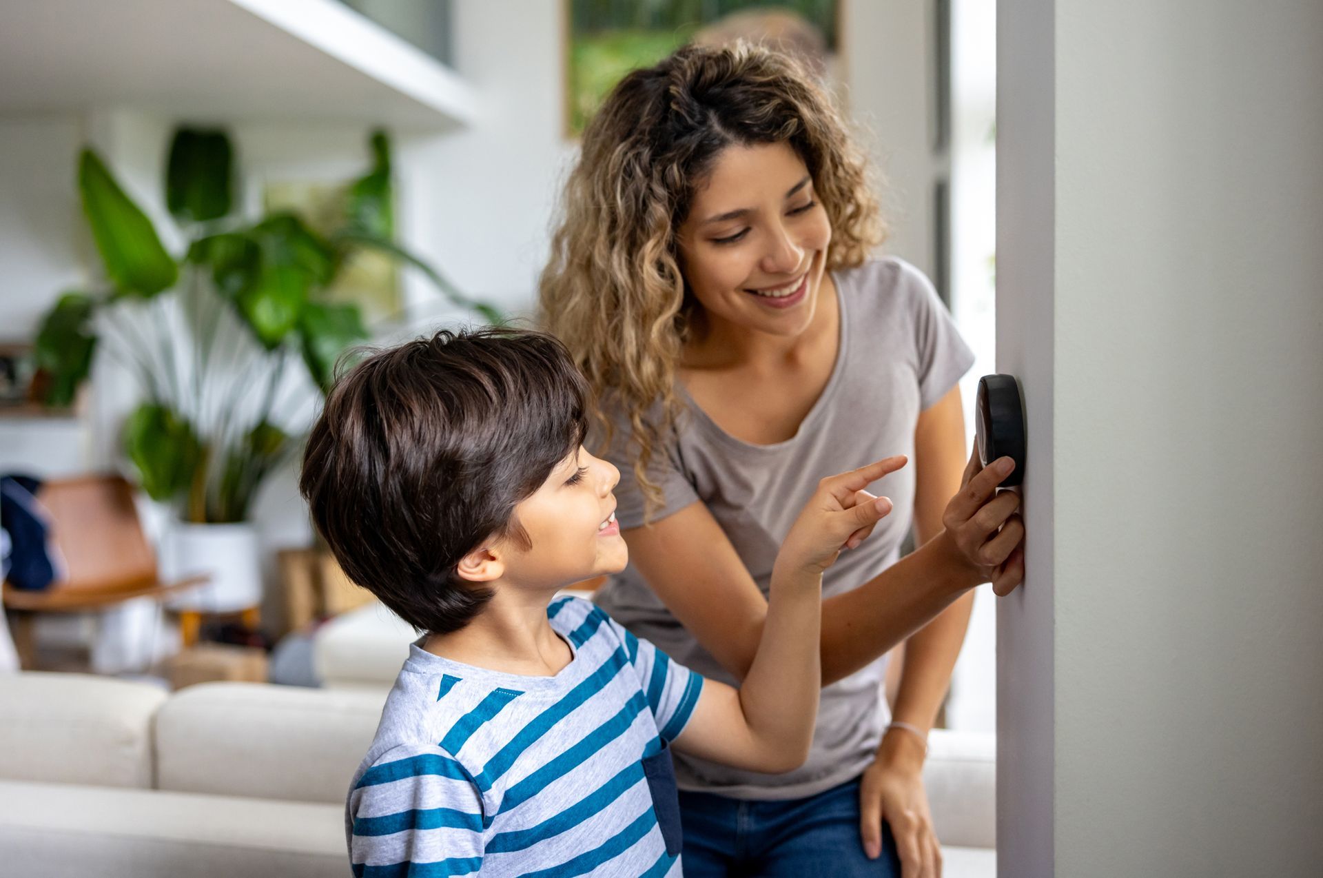 Mother and son at home using a smart thermostat system for efficiency in a California home during wi