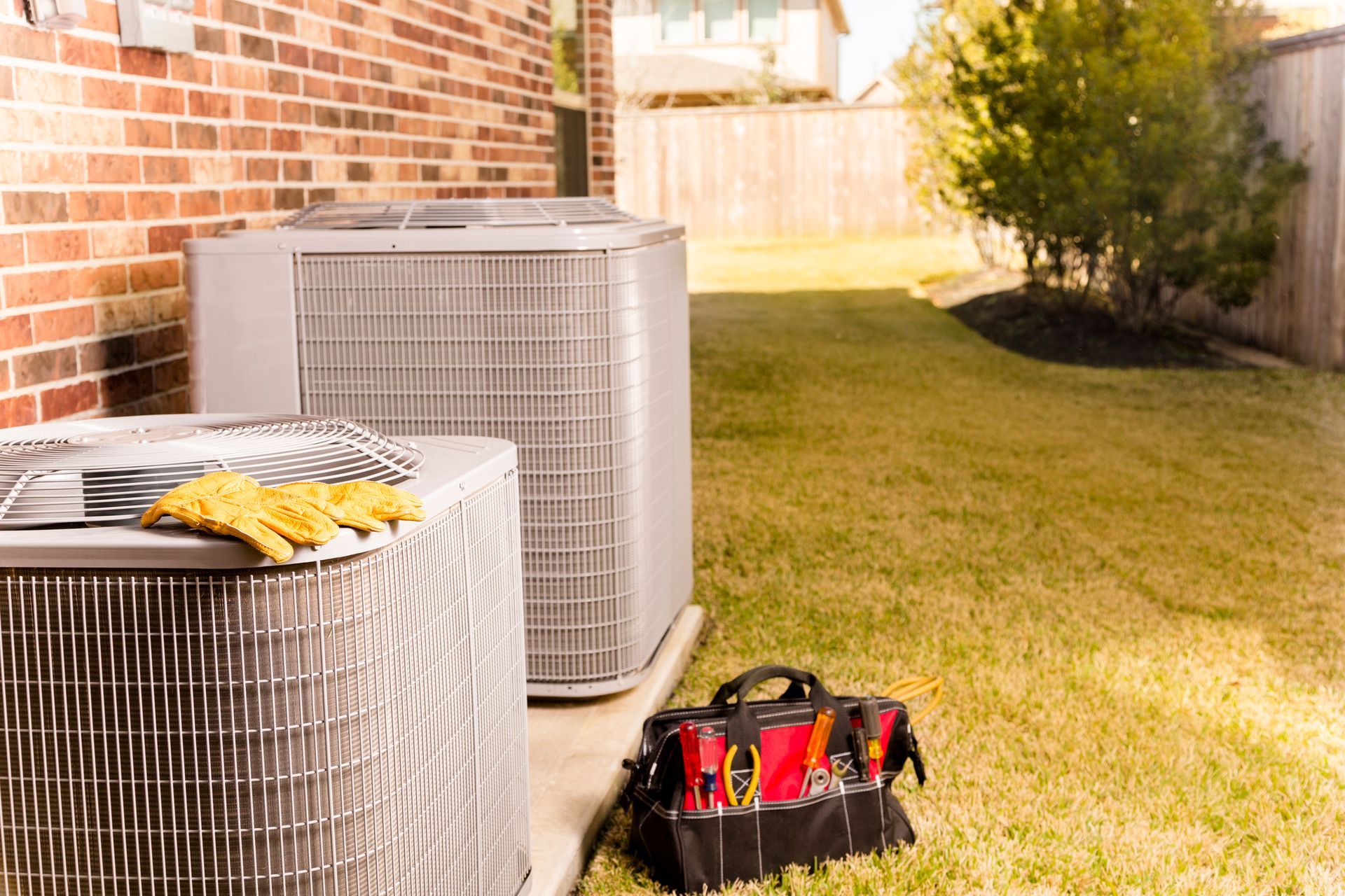 HVAC tools and outdoor air conditioning unit beside a home, illustrating maintenance and efficiency.