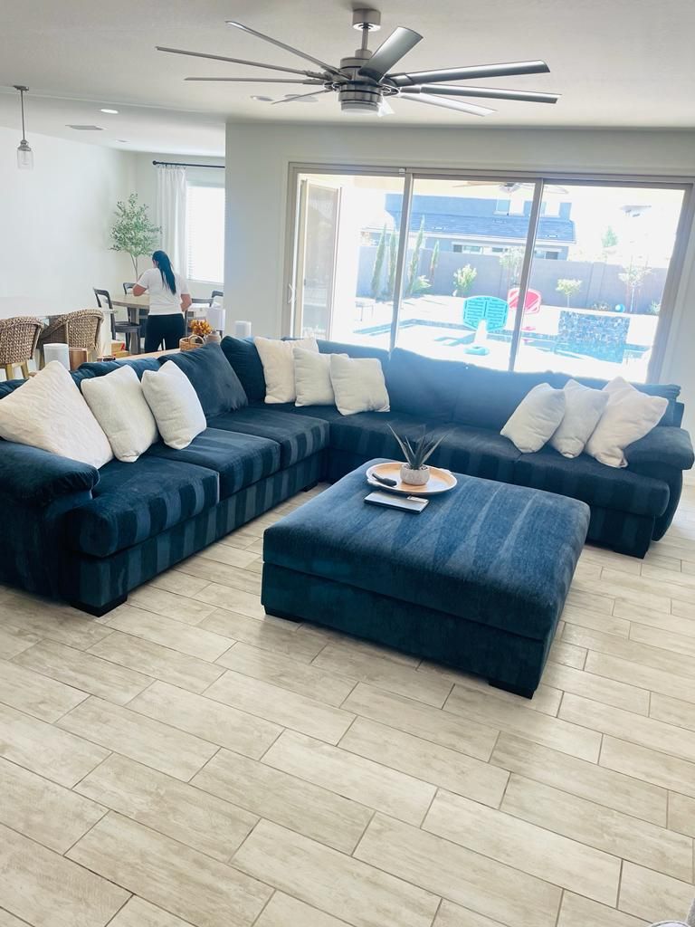 A living room with a large sectional couch and an ottoman