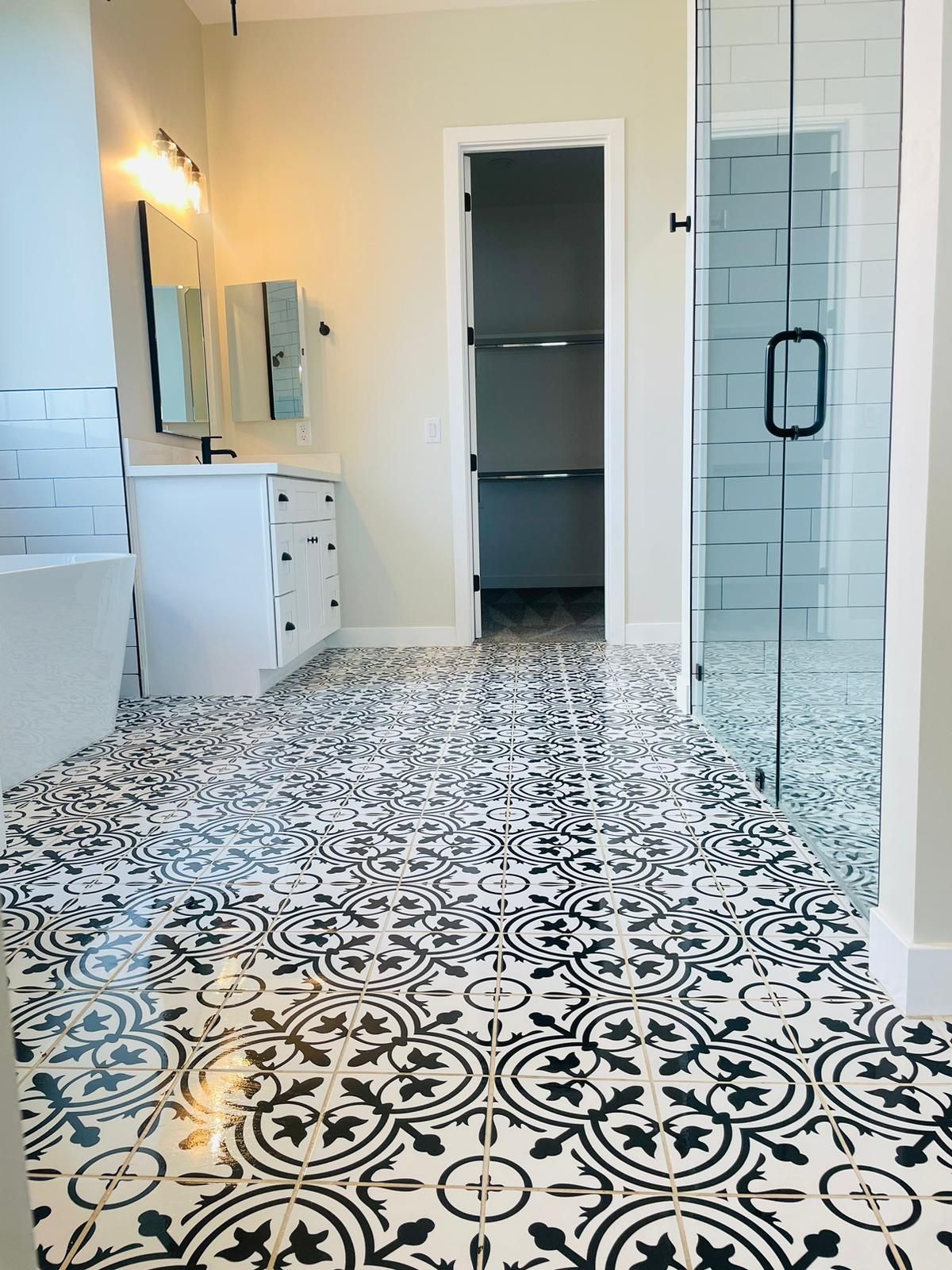 A bathroom with a black and white tile floor and a walk in shower.
