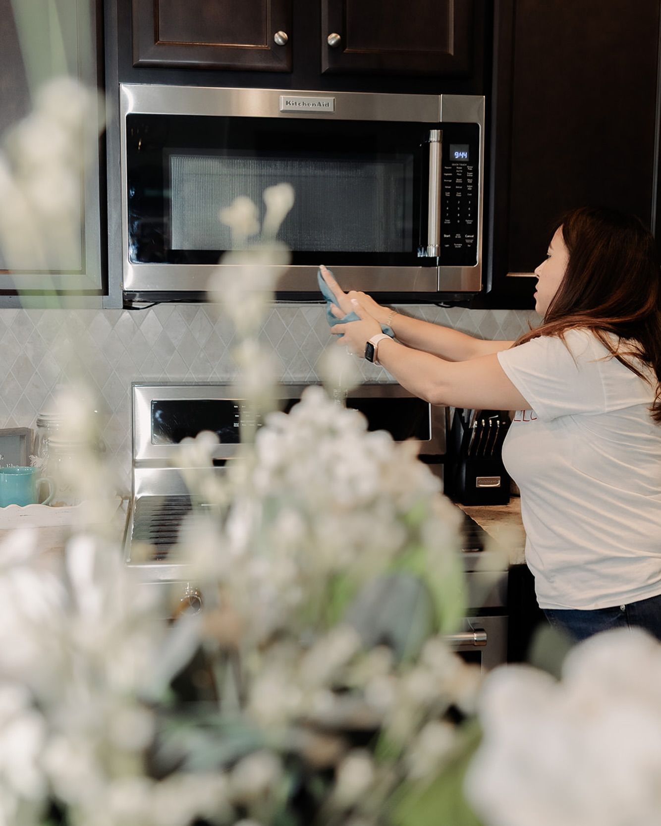 A woman is cleaning a microwave in a kitchen