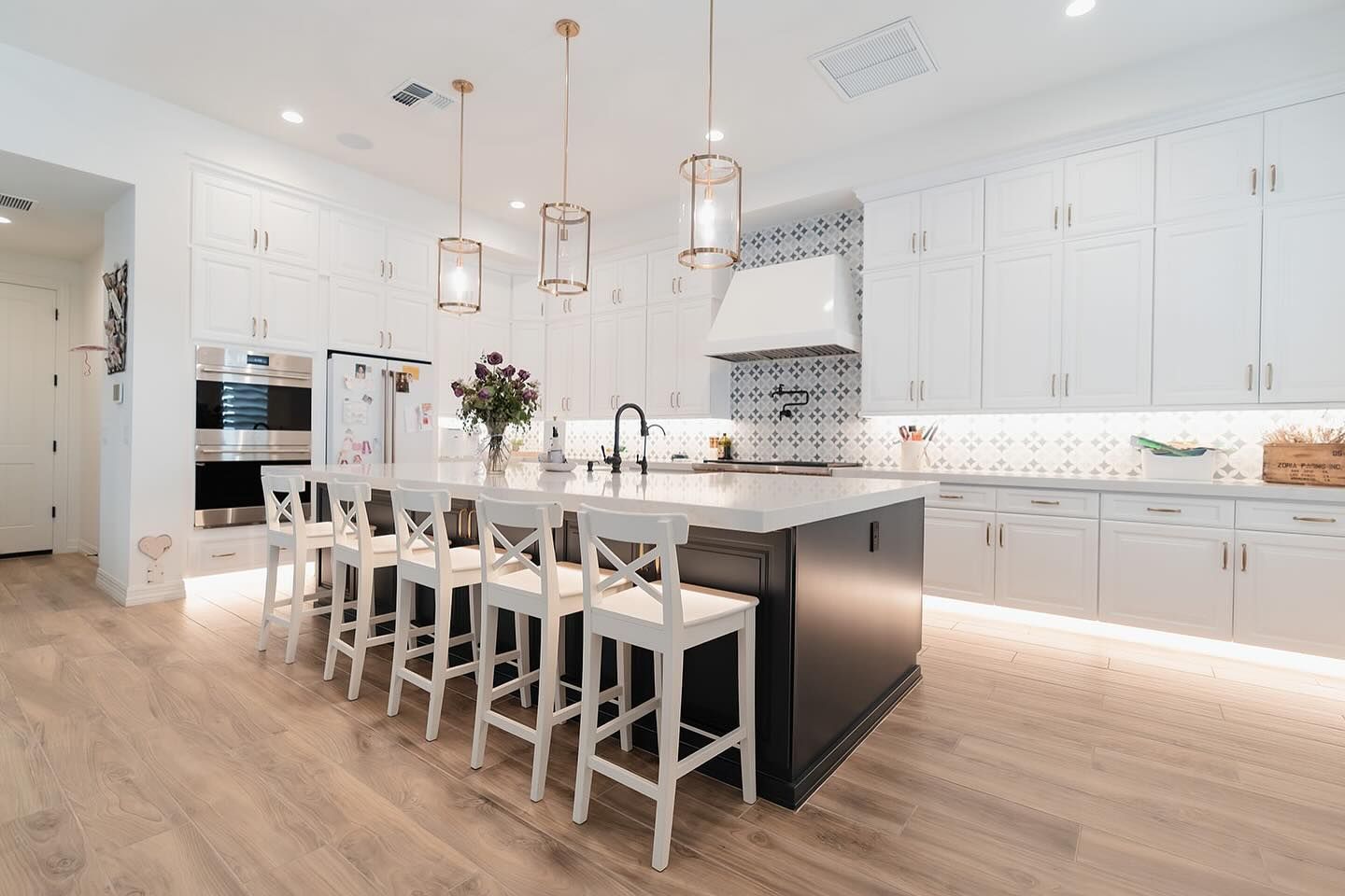A kitchen with white cabinets and stools and a large island.
